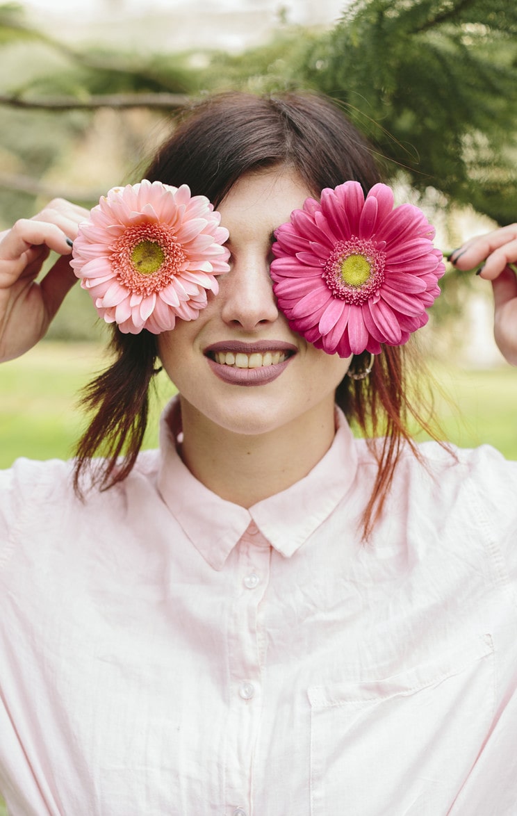 young woman covering eyes flowers smiling scaled